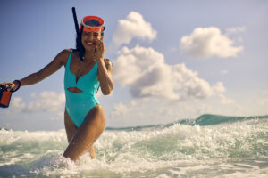 Woman in teal swimsuit snorkeling in the ocean, enjoying a sunny vacation day.