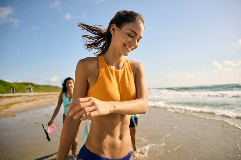 Woman in a bikini walking on the beach with friends.